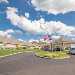 A welcoming entrance to a building with a prominent American flag and a clear, cloudy sky.