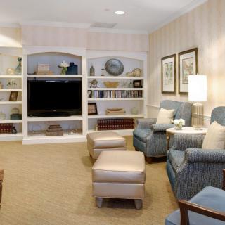 A cozy living room with armchairs, a large television, and built-in bookshelves filled with decor and books.