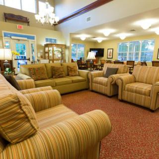 A cozy living room with comfortable sofas and armchairs, softly lit by a chandelier.