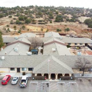 Aerial view of a building with a parking lot and surrounding landscape.