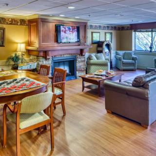 A cozy living room with a seating area, fireplace, and wooden flooring.