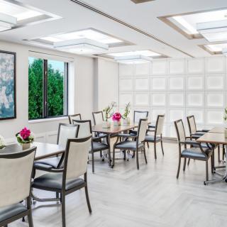 A modern and elegantly decorated dining area with tables and chairs, accented by floral centerpieces.