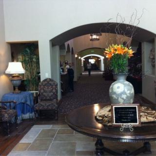 A welcoming lobby area featuring a central table with a decorative vase and flowers, leading into a long hallway.