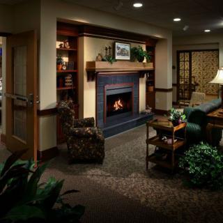 A cozy living room with a fireplace, armchair, and bookshelf.