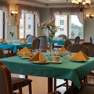 A neatly arranged dining area with tables set for guests, featuring teal tablecloths and folded napkins.