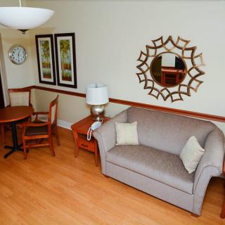 A cozy living room with a sofa, table and chairs, adorned with a decorative mirror and artwork on the walls.