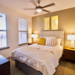 A cozy bedroom with a stylish bed, bedside lamps, and a ceiling fan.
