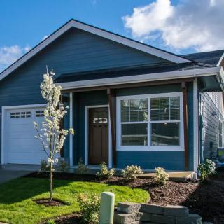 A charming blue house with a landscaped front yard and attached garage.