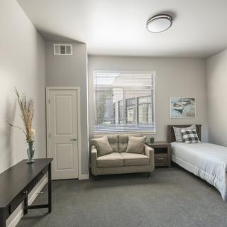 A modern, minimalist bedroom with neutral colors featuring a single bed and sofa.
