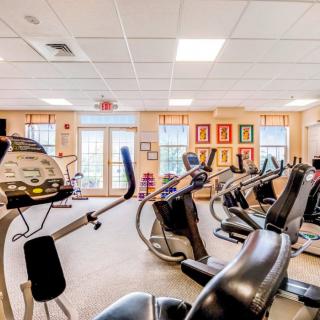 A well-equipped gym with various exercise machines and bright lighting.