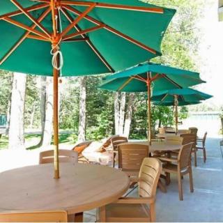Outdoor patio area with wooden tables and green umbrellas.