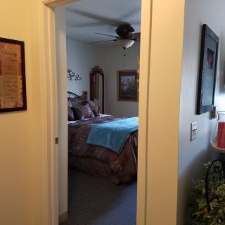 A view into a cozy bedroom through an open doorway, featuring well-arranged furniture and decor.