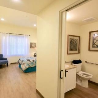 A cozy bedroom connected to an accessible bathroom, featuring simple and modern decor.