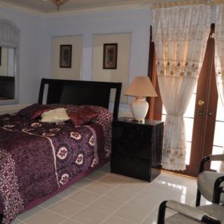 A cozy bedroom with a neatly made bed, nightstand, lamp, and decorative curtains.