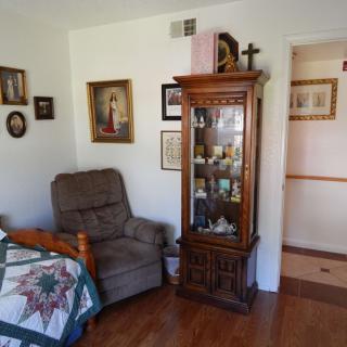 A cozy living room corner with a recliner, quilt, and decorative cabinet.