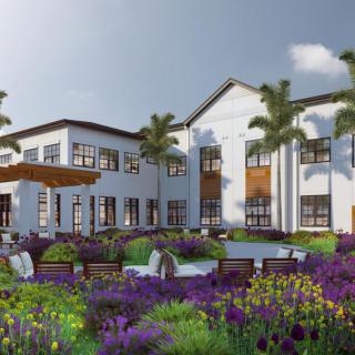 A luxurious house surrounded by a beautifully landscaped garden with vibrant flowers and palm trees.