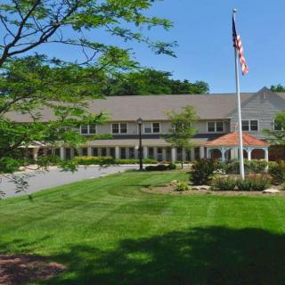 A large building with a neatly maintained lawn and an American flag flying on a flagpole.
