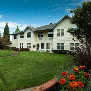 A well-maintained apartment building with lush green lawns and vibrant flower beds.