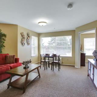 A cozy living room with a red sofa and a small dining area by the window.