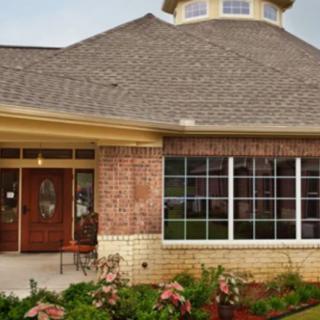 A brick house with a sloped roof and a landscaped garden.