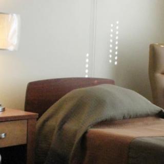 A cozy bedroom with a neatly made bed, a nightstand, and a lamp.