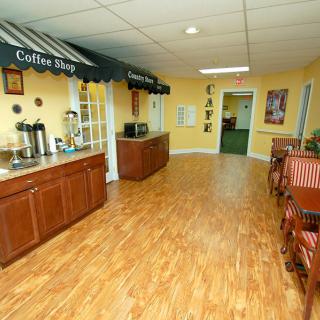 A cozy coffee shop interior featuring a seating area with wooden floors and yellow walls.