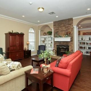 A cozy living room featuring a red sofa and beige couch, with a fireplace surrounded by bookshelves and a hardwood floor.