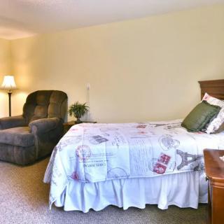 A cozy bedroom with a bed, armchair, and a lamp.