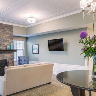 A modern living room with a cozy sofa, wall-mounted TV, and a stone fireplace.