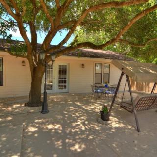 A cozy patio with a large tree providing shade, featuring a swing and outdoor furniture.