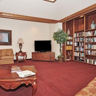A cozy living room with a television, bookshelf, and comfortable seating.