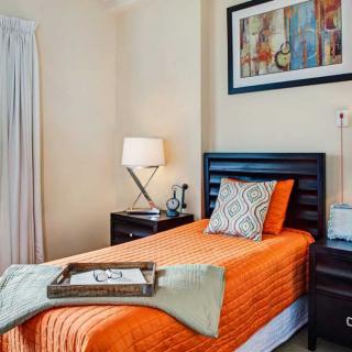 Cozy bedroom with a modern design featuring an orange bedspread and decorative accents.