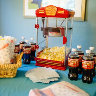 A party setup featuring a popcorn machine and an assortment of drinks on a table.