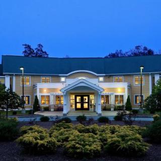 A well-lit building with a symmetrical entrance surrounded by landscaped gardens during the evening.