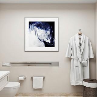 A modern minimalist bathroom featuring a framed abstract artwork and a hanging robe.