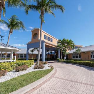 A sunny view of a building with palm trees and a circular driveway.
