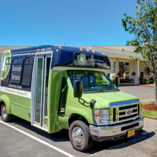A green shuttle bus parked in a sunny parking lot.