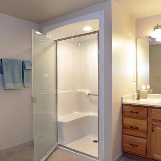 A modern bathroom featuring a walk-in shower with a glass door, wooden cabinets, and soft lighting.