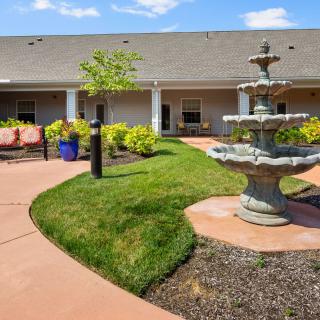 A serene courtyard with a central fountain, surrounded by manicured gardens and outdoor seating.