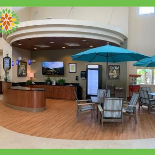 A spacious lobby with a reception desk, seating area, and large umbrellas indoors.