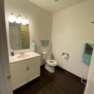 A clean and well-lit bathroom with a vanity, mirror, and toilet.