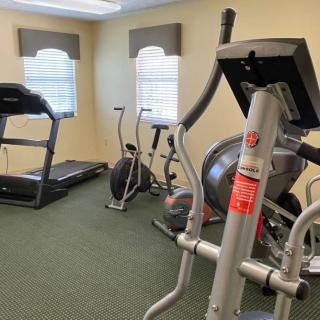 A compact gym room with various exercise equipment including a treadmill, stationary bikes, and an elliptical machine.