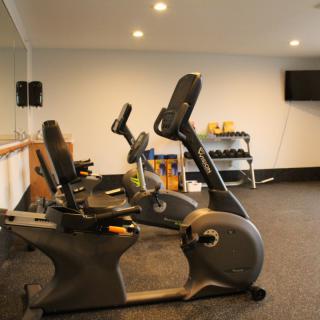 A modern gym with stationary bikes and dumbbells arranged in a workout room.