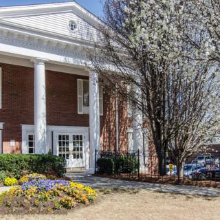 A classical-style building with prominent columns and a landscaped entrance.