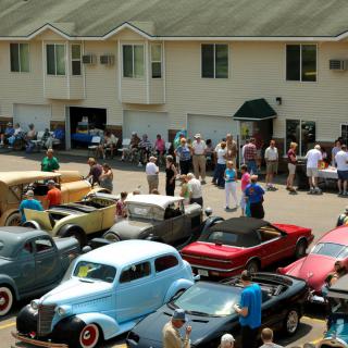 A lively car show featuring a collection of vintage and classic cars with attendees enjoying the event.