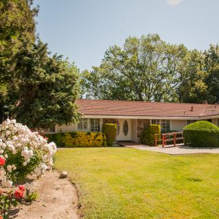 A ranch-style house with a neatly manicured lawn and blossoming garden.
