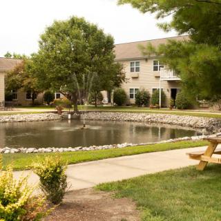 A serene courtyard with a pond surrounded by greenery and buildings.