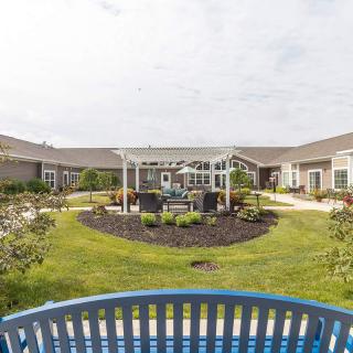 A well-maintained courtyard garden surrounded by buildings with a blue bench in the foreground.