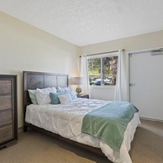 A cozy bedroom with a neatly made bed and a large window.