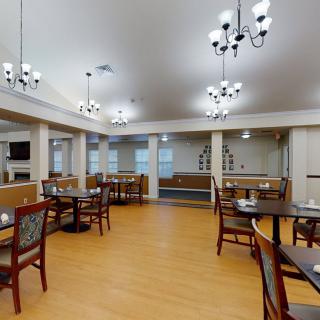 A spacious dining area with wooden tables and chairs, illuminated by elegant chandeliers.